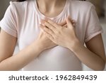 Small photo of Grateful young woman applying hands on chest, expressing love, honesty. Cropped shot of girl in casual t-shirt making gratitude arms heart, thanking, sympathy, acknowledgement gesture. Close up