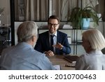 Small photo of Happy confident lawyer, realtor, notary, financial advisor giving consultation, legal advice to senior couple of clients about medical insurance, wills, house buying or selling, savings, investment