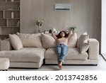 Small photo of Calm millennial Latino woman lying relaxing on couch in living room breathe fresh ventilated condition air. Happy young Hispanic female renter rest on sofa at home relieve negative emotions.
