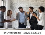 Small photo of Smiling multiracial businesspeople congratulate colleague with job success or achievement. Happy supportive diverse multiethnic employees greet excited male worker with work promotion.