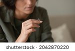 Small photo of Depressed sad young woman taking off and holding wedding ring. New widow feeling emotional pain, grieving after loss. Divorcee going through depression, apathy, heartbreak crisis. Close up