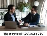 Small photo of Two happy smiling businessmen shake hands in office after making successful deal. Satisfied young man customer appreciate lawyer banker financial counselor for help assistance good consultation advice