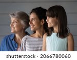 Small photo of Happy daughter and granddaughter kid posing with mom and grandma, standing in row, looking away, smiling. Three Latin family female generations, 7s girl, young, senior women portrait
