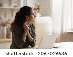 Serious pensive woman sit in kitchen at table with opened laptop looks into distance thinking, ponder, distracted from telecommuting, search for solution, daydream alone at home. Modern tech concept