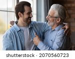 Small photo of True friends. Excited elderly dad embrace adult son glad to hear good news congratulate with success show thumb up. Happy older age male proud of grown child achievement support approve young man deed