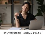 Small photo of Putting job on pause. Calm latina woman relax at desk take break from computer work hold eyewear in hand give rest to tired eyes. Young lady employee sit on workplace with closed eyes take glasses off