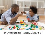 Small photo of Proud dad and happy little son bumping fists over toy blocks and railway model on heating floor. Father giving praise to kid, expressing approval, enjoying friendship, fatherhood, playtime