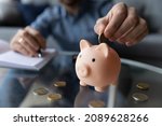 Small photo of Personal savings, planning budget and money for future, frugal person concept. Close up male hand putting eur coins into piggy bank. Thrifty man add cash in moneybox thinks about tomorrow, makes stash