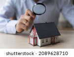 Man appraiser hold magnifying glass examining cottage house miniature, bank officer using zoom checking assessment of dwelling. Concept of real estate appraisal, property, land valuation, house search