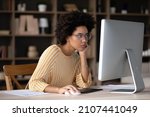 Small photo of Thoughtful young African American business woman looking at computer monitor, feeling exhausted working on difficult tasks, considering project problem solution, analyzing data preparing document.