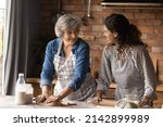 Small photo of Happy Latin grown up daughter and senior mother cooking in home kitchen together, rolling dough for homemade pastry, bakery food, talking, laughing, enjoying leisure time, common hobby together