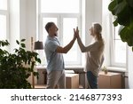 Small photo of Mature couple accomplish relocation day give high five feel happy, standing in unfurnished living room with heap of cardboard boxes. Move celebration, bank mortgage for older citizen, new life concept
