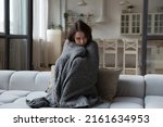 Small photo of Sick unhappy girl wrapped in warm plaid suffering from cold, fever, high body temperature. Young patient woman feeling unwell, ill due to virus, flu. Healthcare, epidemic concept