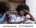 Small photo of Teen African girl express her claim in aggressive manner to boyfriend sit nearby looks annoyed, ignoring girlfriend, feels disinterested to sort out their relationships. Bad relations, quarrel concept