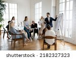 Small photo of Confident male boss or trainer make whiteboard presentation for diverse employee at team office meeting. Businessman talk lead briefing, present project on flip chart at team training or briefing.