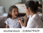 Indian female therapist training kid with hearing disability, deafness to use fingers for communication. Mom and cute daughter kid speaking sign language, talking, using hand gestures