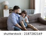Small photo of Loving dad listen with interest his little son, sit on sofa spend time together, enjoy conversation, trustworthy communication having warm friendly relations. Understanding, family, fatherhood