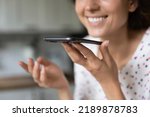 Crop close up of smiling woman talk speak on loudspeaker on modern smartphone gadget. Happy female technology client user activate voice assistant app on cell, record audio message on cellphone.