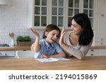 Small photo of Little cute boy finish schoolwork giving high five to Asian tutor. Loving mother praising her 7s son for good result, well done assignment. Help, symbol of success, teamwork and homeschooling