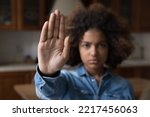 Small photo of Serious African teenager girl looking at camera raises her palm showing stop gesture, against emotional and physical abuse, bullying at school, racial inequality, struggling for women rights, close up