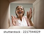 Happy laughing young woman putting arms into box, feeling excited receiving order from internet store. Joyful female customer satisfied with fast delivery service, getting parcel, shipping concept.