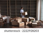 Small photo of Millennial man carrying packed cardboard boxes with personal belongings to unfurnished cozy living room during move-in relocation day to new first own apartment. Tenancy, bank mortgage, independence