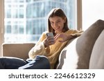 Small photo of Beautiful young woman rest on sofa use mobile phone, enjoy leisure on internet, have fun use new mobile application spend time alone in sunny warm living room at home. Lifestyle, modern gadget usage