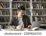 Small photo of Happy student guy, teenage schoolboy prepare assignment, learn theory, studying in library using laptop. Generation Z gain new knowledge using modern wireless tech and internet resources. Education