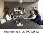 Small photo of Office staff meeting with diverse freelance team on online video conference, making group call on internet, sitting at table looking at electronic board with head shots, discussing work project