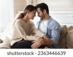 Small photo of Happy loving man and woman enjoying tender moment with closed eyes, touching foreheads, expressing unity and care, beautiful girlfriend sitting on boyfriend laps, relaxing on cozy couch at home