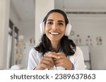Happy beautiful Latin doctor woman in headphones head shot portrait. Young practitioner, medical therapist giving online consultation on video call, speaking from screen with toothy smile