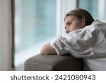 Lonely young woman lies on sofa, looking out window, having melancholic mood, suffer of unrequited love, break up, feel depressed, unhappy alone at home, pensive attractive female thinks about problem