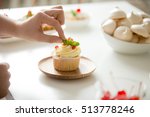Close up of female hand topping a cupcake with refreshing mint leaf or picking it. Pastry chef woman making sweet dessert cake. Horizontal image