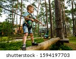 Small photo of Go Ape Adventure. Climber child on training. Child climbing on high rope park. Roping park. boy with safety carbine goes on a rope in adventure climbing high wire park