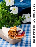 Small photo of Greek fast food delivery.Gyros sandwich with fried meat wrapped in paper. Gyro pita take away, street food pita bread wraps with meat, traditional greek food on wooden table