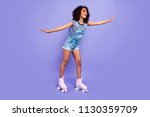 Full body portrait of positive funky girl learning to ride on roller skates keeping balance enjoying activity isolated on bright violent background retro vintage quad student concept
