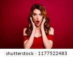 Advertising concept. Portrait of gorgeous, good-looking, alluring, magnificent woman with palms near the face, big eyes, open mouth and modern hairdo isolated on deep red background