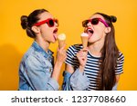 Two cute gorgeous nice adorable good-looking nice-looking brunette hair lady in glasses spectacles eating sugar yummy delicious sweet appetiser snack isolated on yellow wall