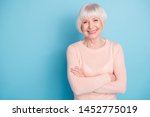 Portrait of lovely lady with her arms folded having toothy smile wearing pastel sweater isolated over blue background