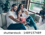 Portrait of nice attractive lovely positive glad cheerful cheery family wearing casual white t-shirts jeans denim sitting on divan having fun watching video switching channel spending free time