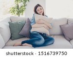 Small photo of Photo of pretty lady holding big pillow close to chest closing eyes glad get rest after hard working week sitting sofa wearing jeans clothes apartment indoors