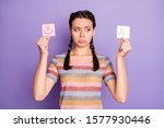 Photo of gloomy lady holding paper emoticons good and bad mood prefer negative emotions awful day wear casual striped t-shirt isolated pastel purple color background