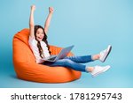 Small photo of Portrait of nice attractive cheerful cheery excited glad wavy-haired girl sitting in chair using laptop celebrating win isolated on bright vivid shine vibrant blue teal turquoise color background