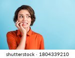 Oops. Closeup photo of sad terrified lady horrified facial expression made big mistake feel guilty look side empty space bite lips fingers wear orange shirt isolated blue color background