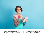 Photo portrait of curious girl thinking about idea keeping pen notebook looking at copyspace isolated on bright color blue background