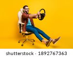 Full length body photo of playful crazy man in chair holding steering wheel pretending car rider isolated vivid yellow color background