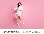 Full length body size photo of dancing woman in long dotted dress jumping looking blank space isolated pastel pink color background