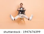 Full size photo of happy excited crazy attractive man in glasses riding car fast extreme isolated on beige color background