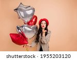 Photo portrait of woman with helium balloons sending air kiss isolated on pastel beige colored background