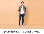 Full body photo of charming cheerful positive young man hold hands pockets isolated on beige color background
